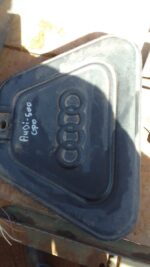 Front view of a used Audi 500 engine cover with mounting points and weathered surface details.Front view of a
