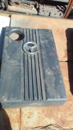 Front view of a used black plastic engine cover for a Mercedes W202, slightly angled to show detail.Front view