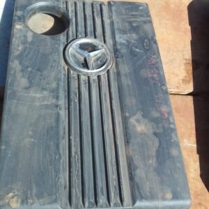Front view of a used black plastic engine cover for a Mercedes W202, slightly angled to show detail.Front view