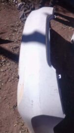 Rear view of a used Nissan Almera rear bumper showing mounting points and slight wear.Rear view of a used Niss
