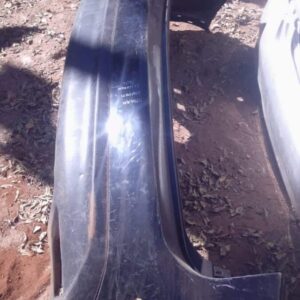 Rear view of a used Infiniti FX37 rear bumper displayed flat on a surface with minor wear visible.Rear view of