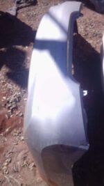 Rear view of used Nissan Almera rear bumper, showing full rear panel with mounting points visible.Rear view of