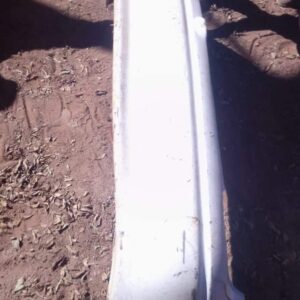 Used rear bumper for Opel Corsa Lite shown from an angled front view with mounting points visible.Used rear bu