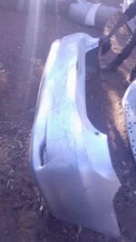 Used rear bumper of a 2013 Toyota Corolla, shown from a slightly angled front view on a white background.Used