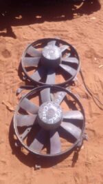 Front angled view of a used radiator fan assembly for Mercedes W202, showing blades and motor housing.Front an