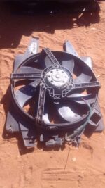 Used radiator fan installed on metal casing, viewed angled from front and side.Used radiator fan installed on