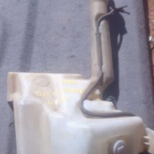 Front angled view of a used Jeep Cherokee windshield washer bottle with attached hose and pump assembly.Front