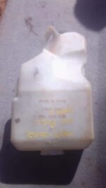 Front-angle view of a used Volkswagen Polo washer bottle showing mounting points and fluid reservoir.Front-ang