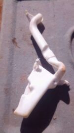 Front-angle view of a used Volkswagen Polo Vivo windshield washer bottle with attached spray nozzle.Front-angl