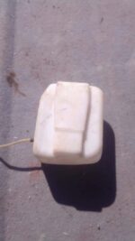 Front view of a used Volkswagen Golf 1 washer fluid bottle with attached cap and mounting points.Front view of