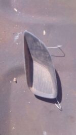 Left side headlight cover for Toyota Yaris, front angle view, used condition, clean surface with minor wear.Le