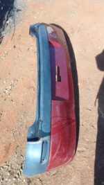 Rear view of a used grey car rear bumper for an Opel Corsa Gamma, slightly curved and intact.Rear view of a us