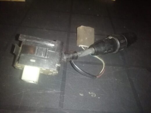 A close-up image of an electrical connector with a rectangular black housing, a white plug, and a black wire extending from it. The background is a dark surface.