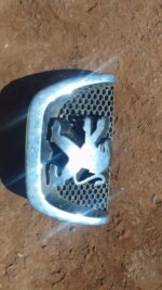 Close-up front view of used Peugeot 206 badge with chrome and black enamel details.Close-up front view of used