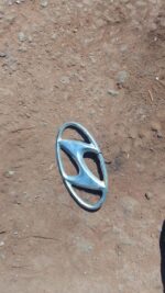Front view of a used Hyundai car badge emblem showing the brand logo in metallic finish.Front view of a used H